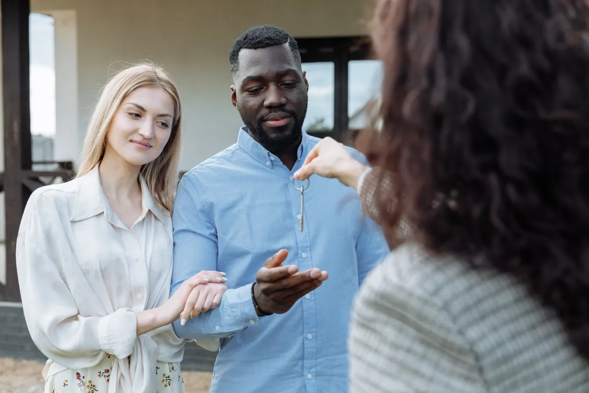 A real estate agent handing house keys to a couple